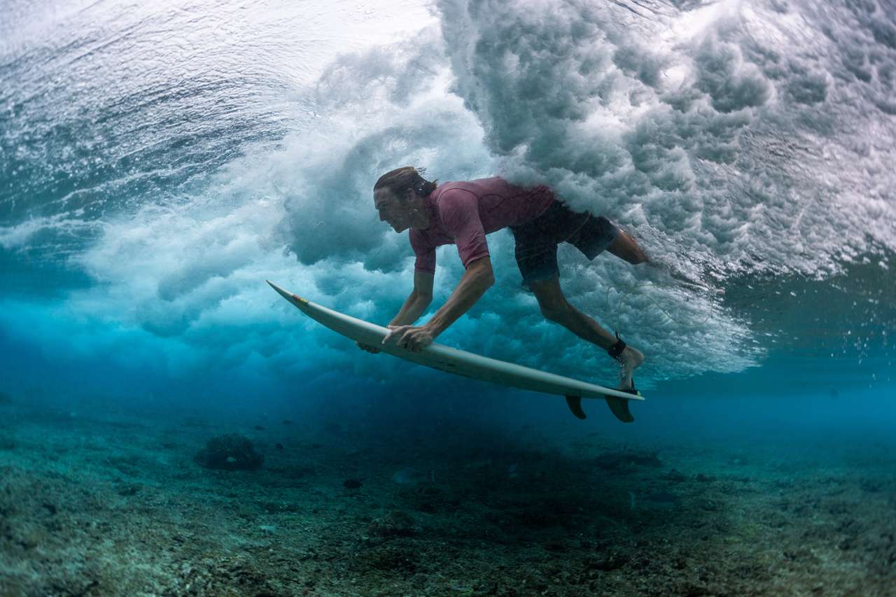 Серфер ныряет под разбивающуюся океанскую волну пазл онлайн