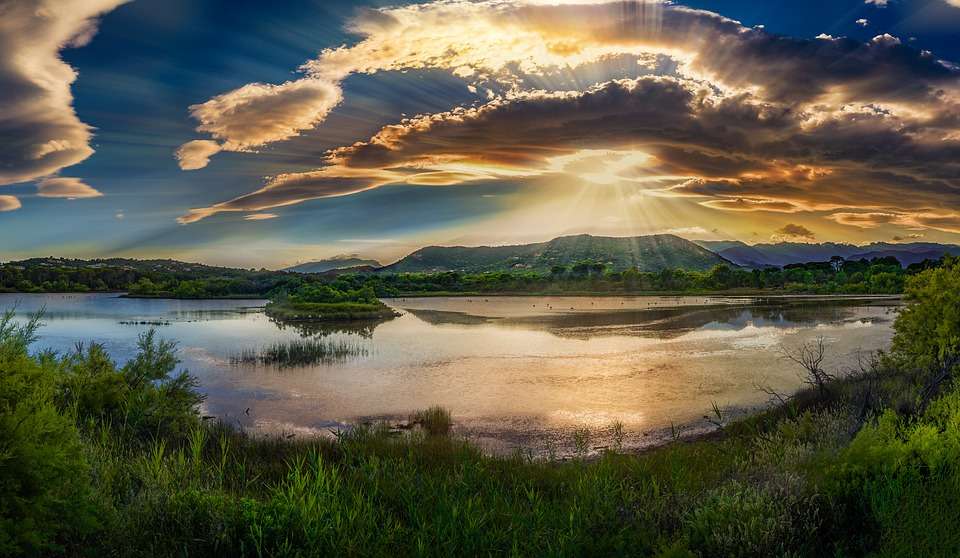Solnedgång återspeglas i sjön Pussel online