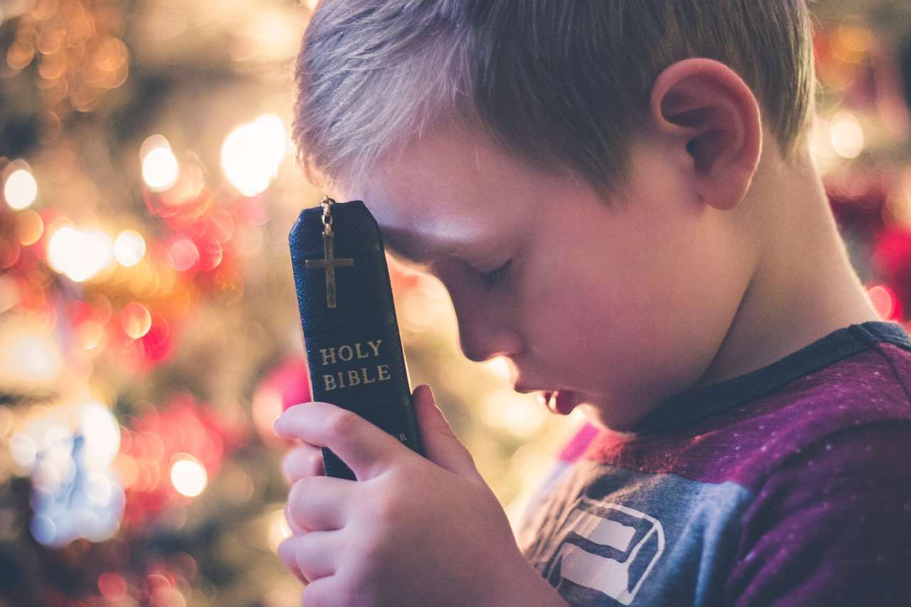 El niño está orando en la Biblia. rompecabezas en línea