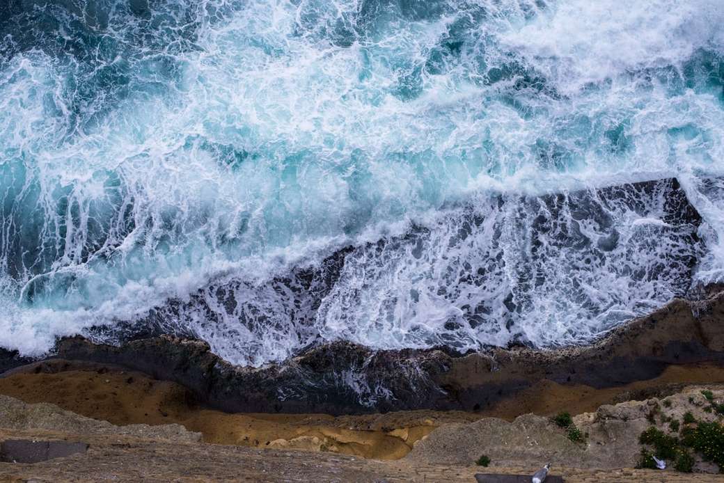Вид с воздуха на волны, разбивающиеся о скалы онлайн-пазл