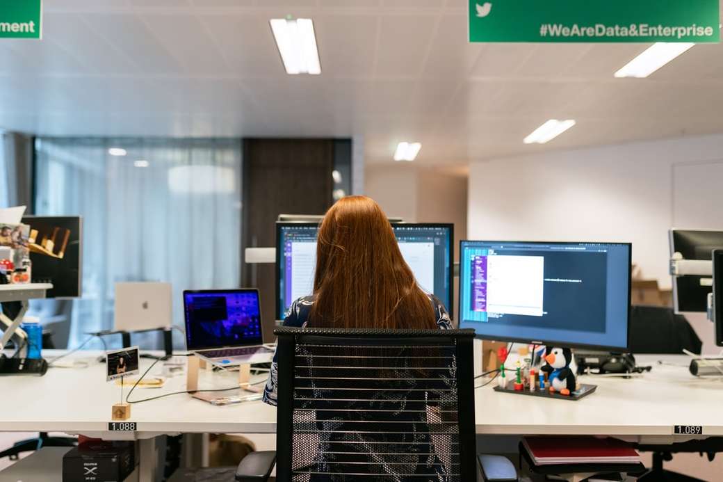 mujer de camisa negra sentada en una silla frente a la computadora rompecabezas en línea