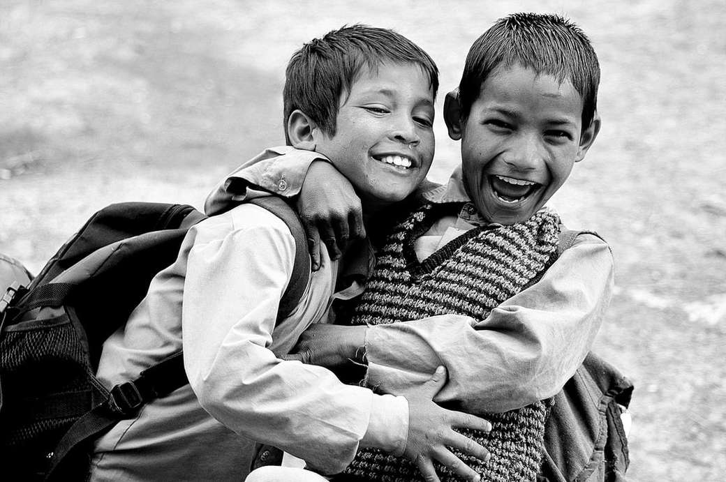 Fotografía en escala de grises de dos niños abrazándose mientras se reían rompecabezas en línea