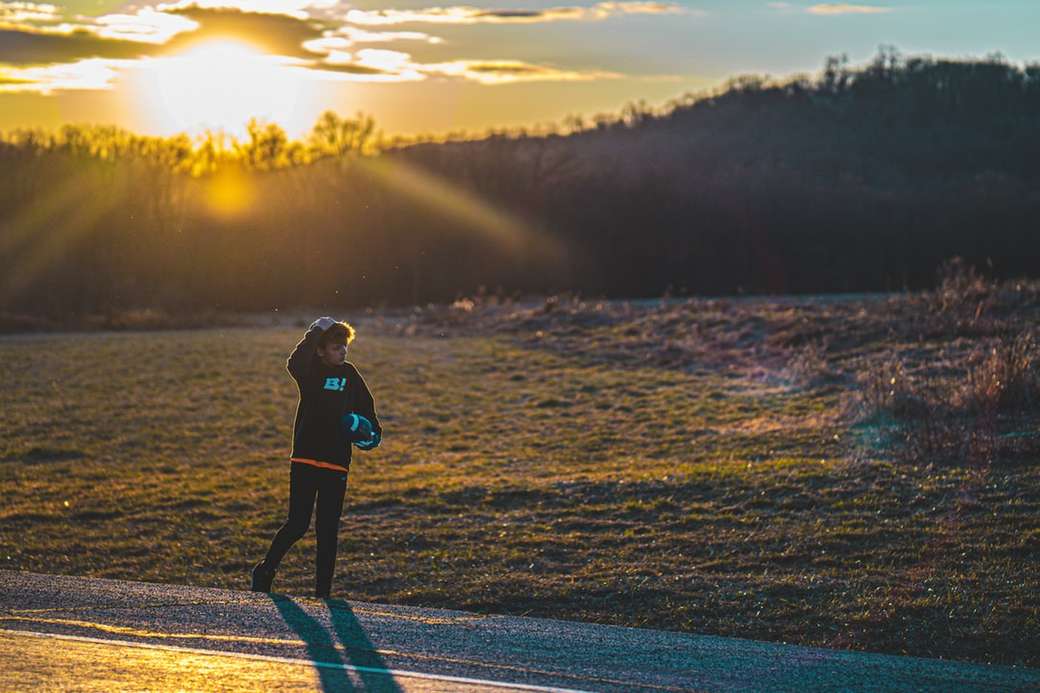donna in giacca nera, camminando sulla strada durante il tramonto puzzle online