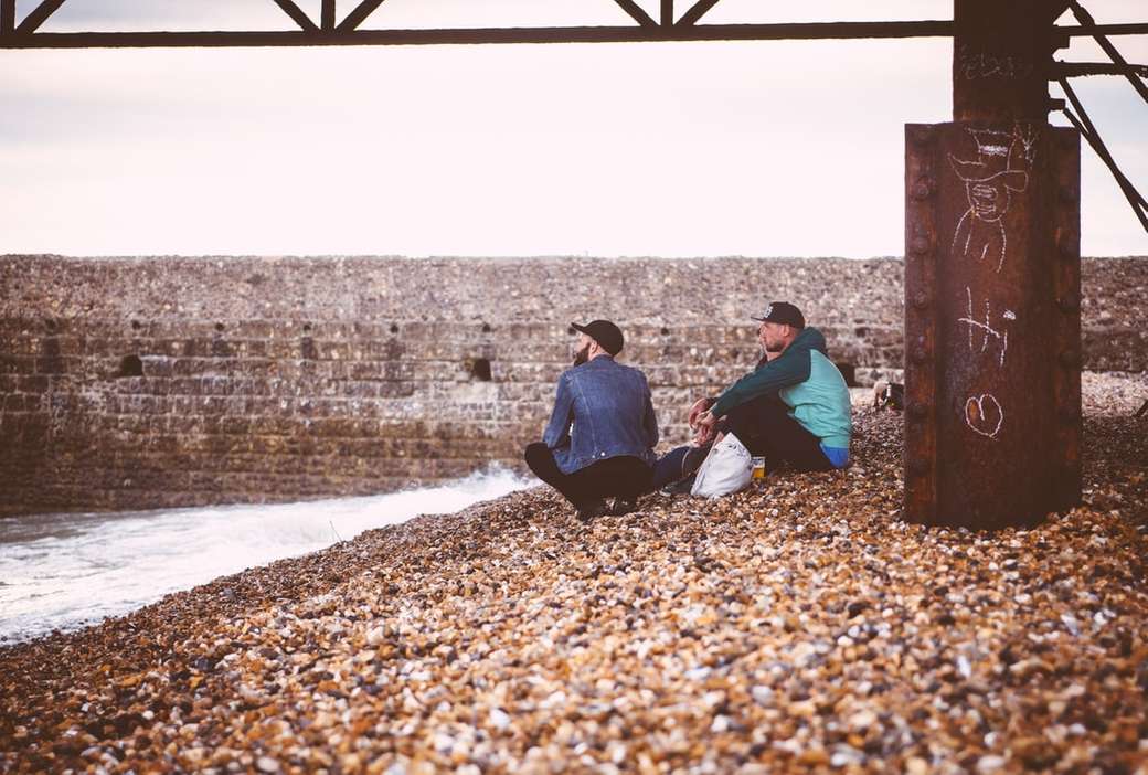 Men sitting on a pebble beach jigsaw puzzle online