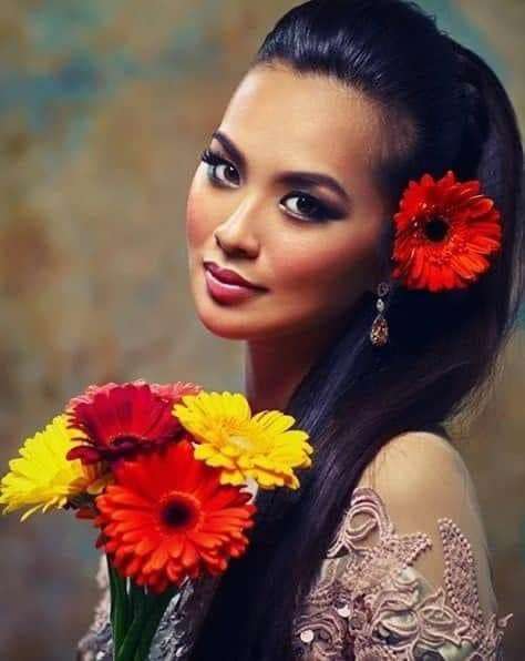 Uma mulher com lindos olhos com flores em suas mãos quebra-cabeças online