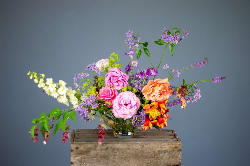 Flores multicolores en jarrón sobre superficie de madera rompecabezas en línea