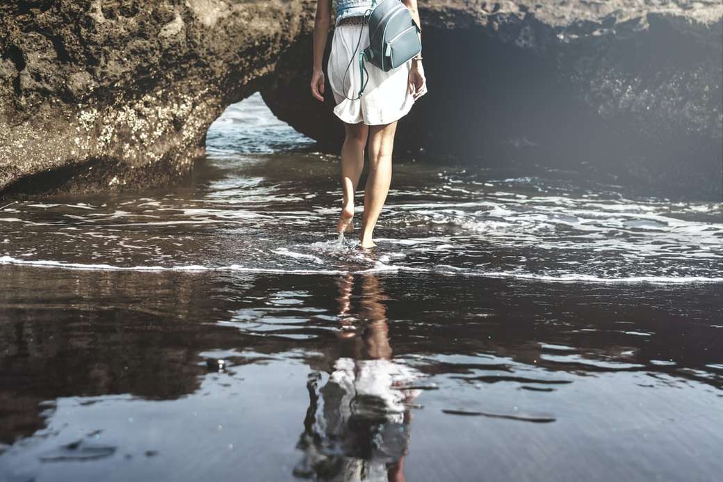 Fiatal nő egy fekete homokos strandon, Bali-szigeten. kirakós online