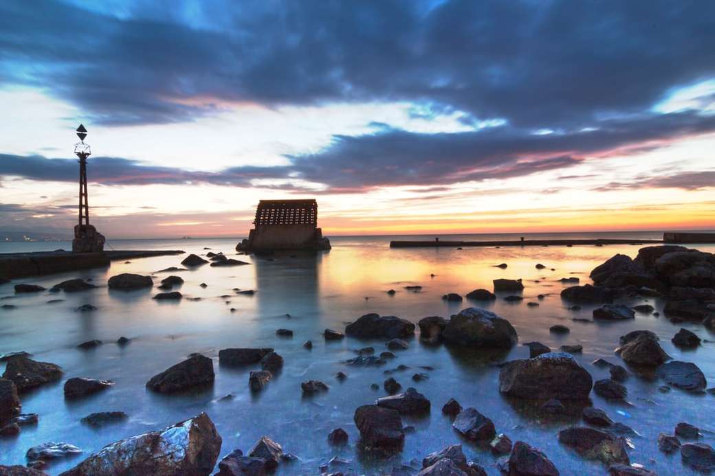 коричневые скалы на берегу моря во время заката онлайн-пазл
