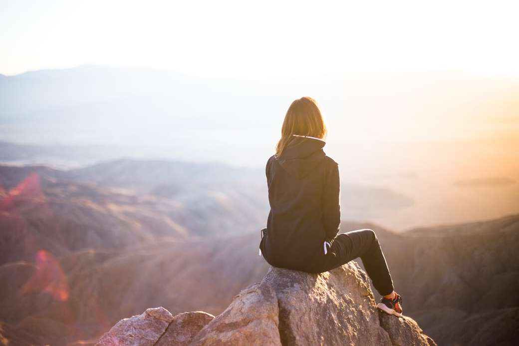persona sentada en la cima de una roca gris con vistas a la montaña rompecabezas en línea