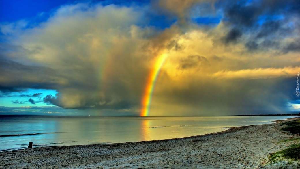 bewölkter Himmel über dem Meer mit einem Regenbogen Online-Puzzle