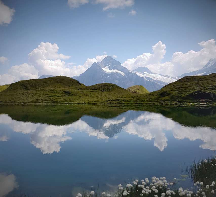 montagne verdi e marroni accanto al lago sotto il cielo blu puzzle online