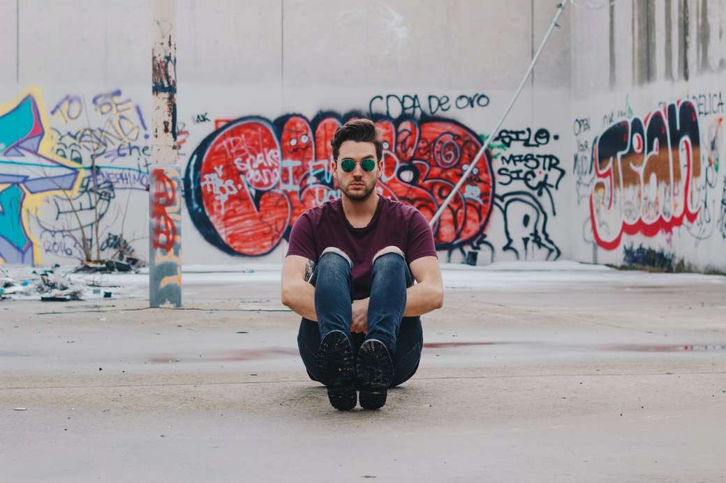 muž na sobě fialové tričko sedí před graffiti zeď online puzzle