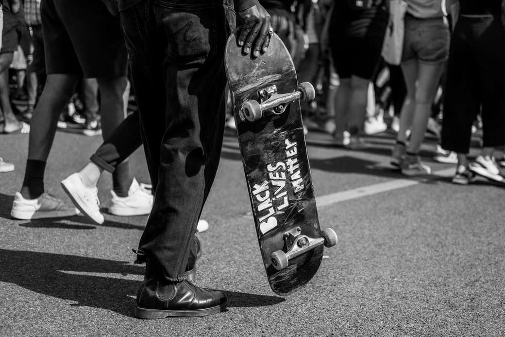 фото у відтінках сірого людини, що тримає скейтборд онлайн пазл