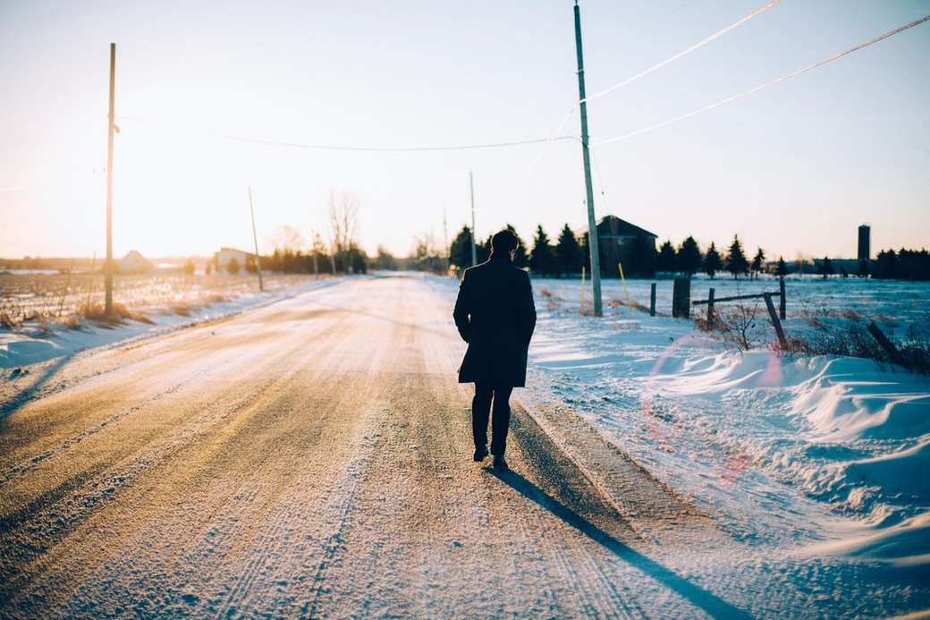 Mann, der in der Mitte der mit Schnee bedeckten Straße geht Puzzlespiel online