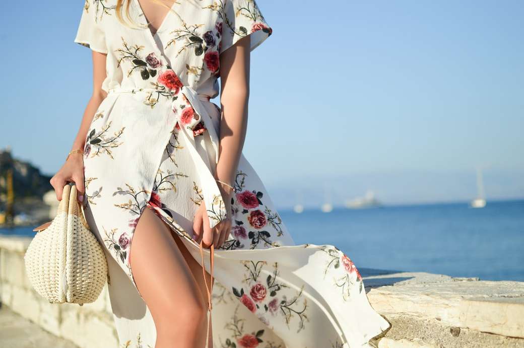 Mujer caminando por la orilla del mar sosteniendo una bolsa tejida rompecabezas en línea