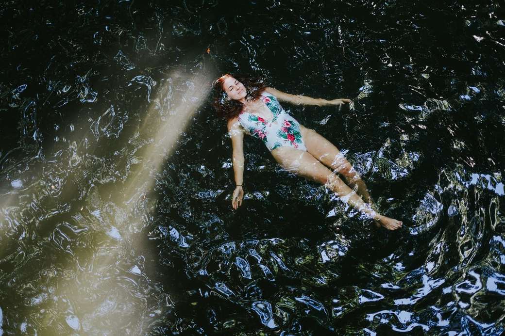 kvinna i blå och vit blommig bikini som ligger på vatten pussel på nätet