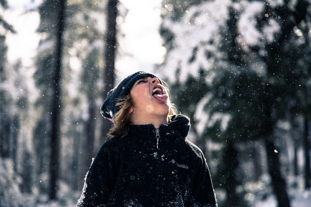 Meisje steekt haar tong uit om sneeuwvlokken te vangen. legpuzzel online
