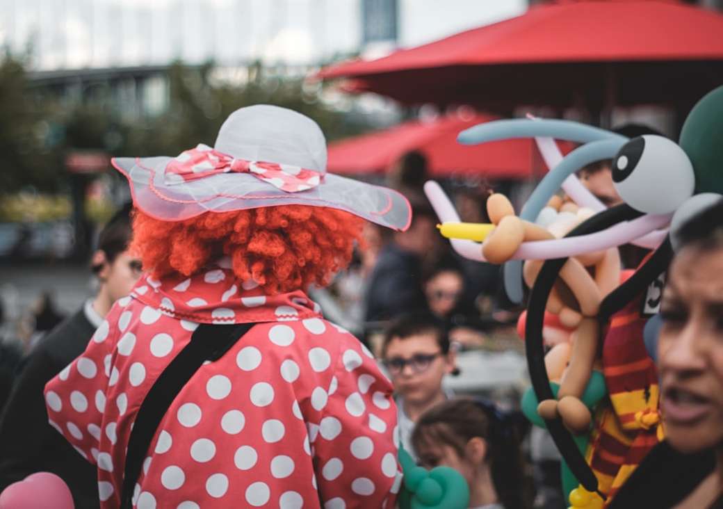 Clow portant un chapeau de soleil blanc entouré de gens puzzle en ligne