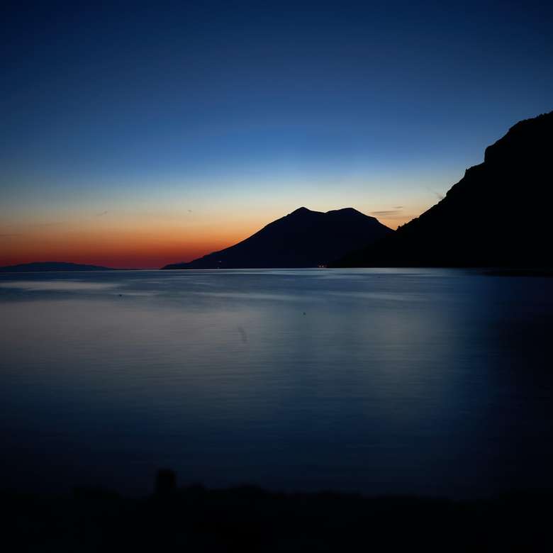 silhouet van berg naast zee online puzzel