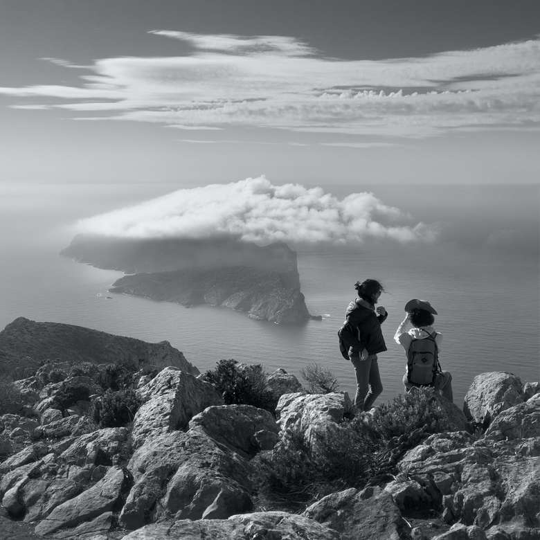 foto in scala di grigi di due donne sulla roccia accanto al mare puzzle online