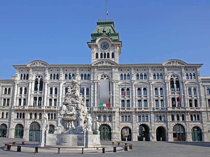 Historisk byggnad med en fontän i Trieste Pussel online