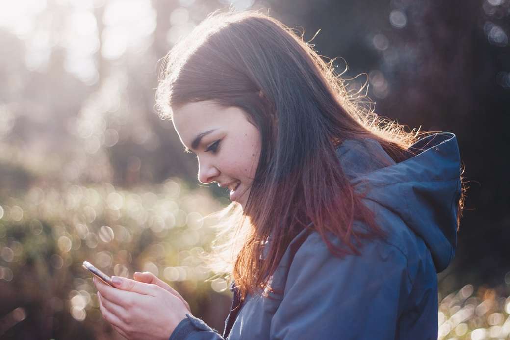 žena drží telefon s úsměvem skládačky online