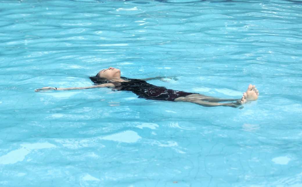Ein junges Mädchen, das auf dem Schwimmbad schwimmt Online-Puzzle