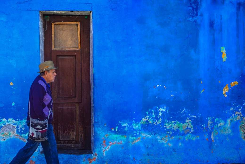 мужчина идет рядом с выкрашенным в синий цвет зданием онлайн-пазл