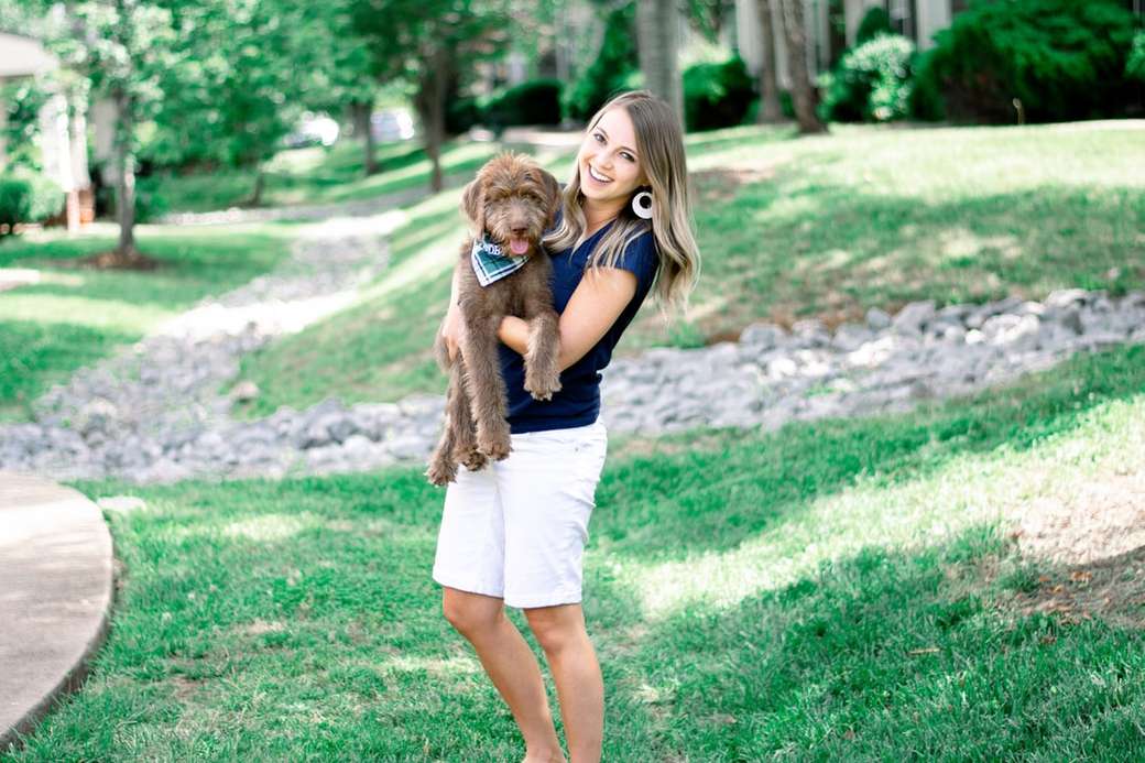 Момиче, което държи кученце, докато се усмихва. онлайн пъзел