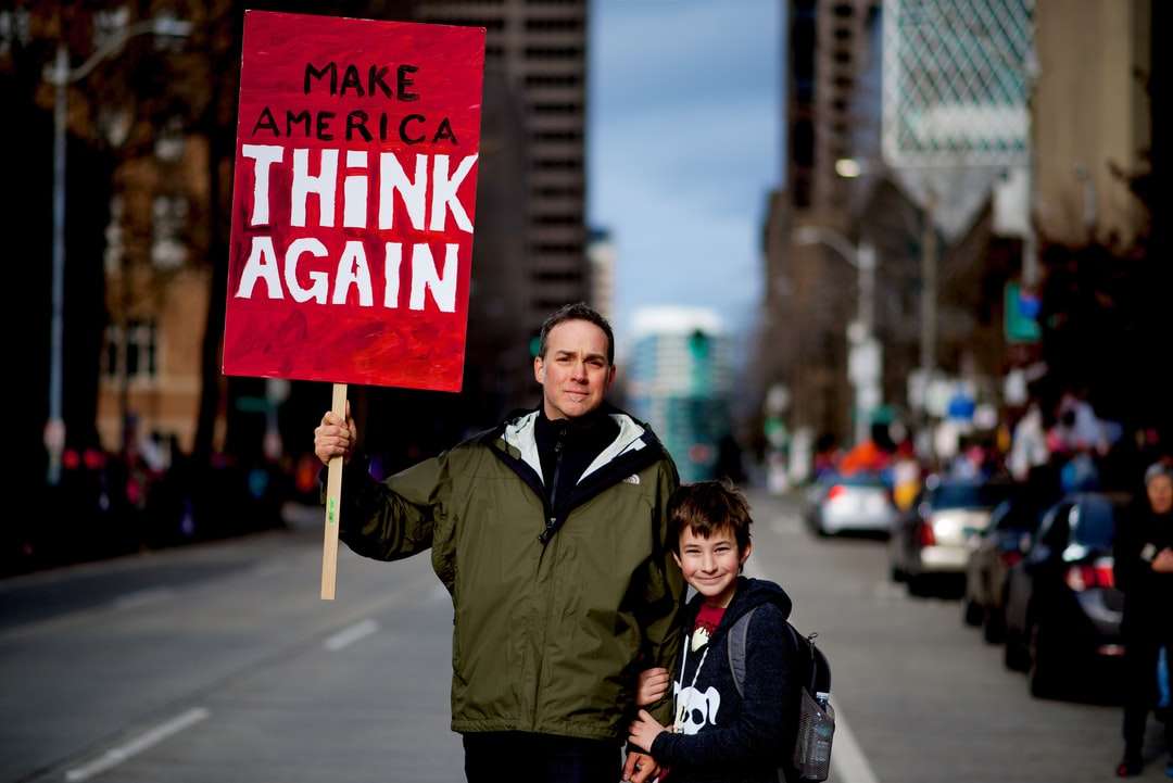 homem ao lado de um menino segurando uma placa vermelha e branca de rally quebra-cabeças online