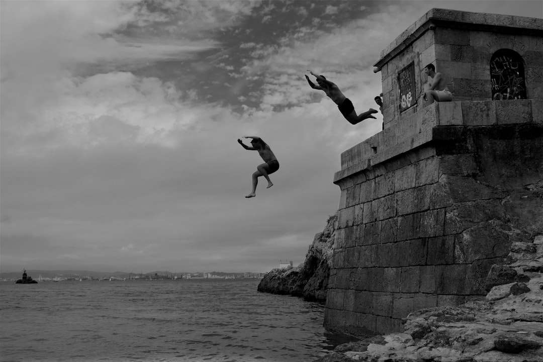 twee mannen duiken vanuit een betonnen gebouw het zeewater in online puzzel