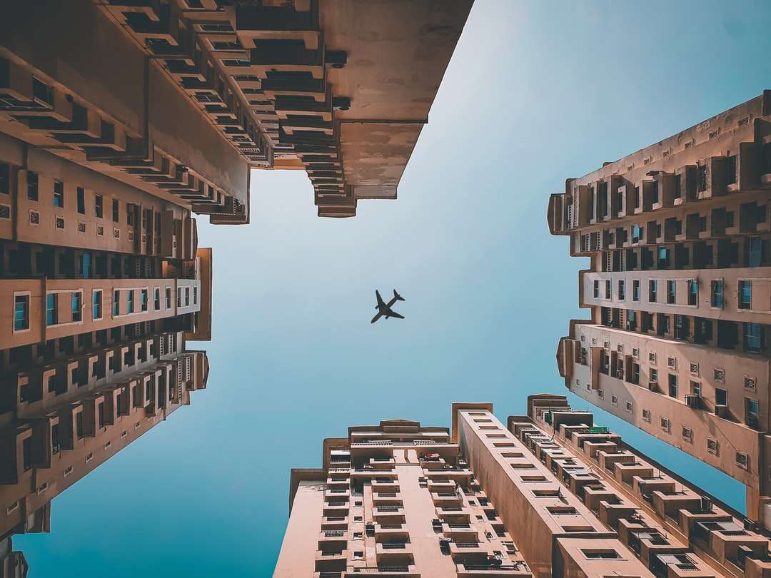 Kijk omhoog shot van een vliegtuig dat over de gebouwen gaat online puzzel