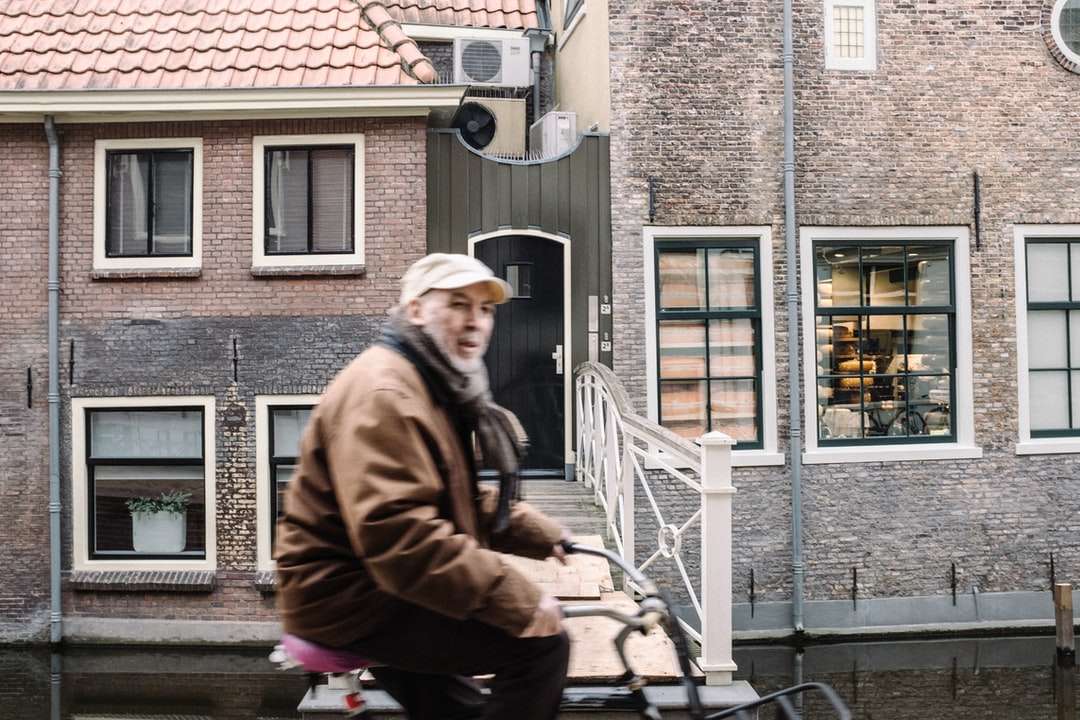 barna kabátos ember ül beton épület mellett online puzzle