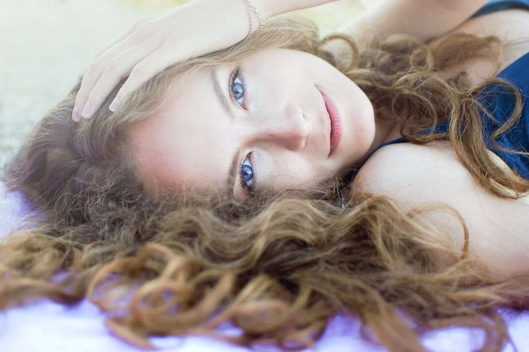 vrouw in paars mouwloos onderhemd liggend op blauw textiel online puzzel