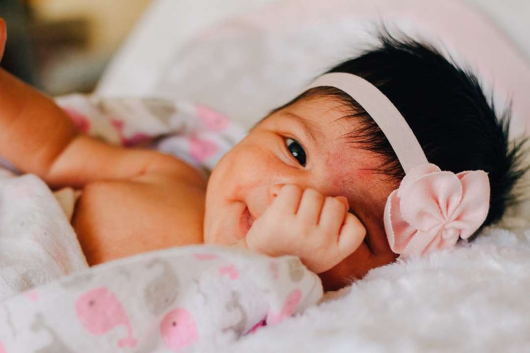baba fehér virágos fejpántot visel az ágyon kirakós online