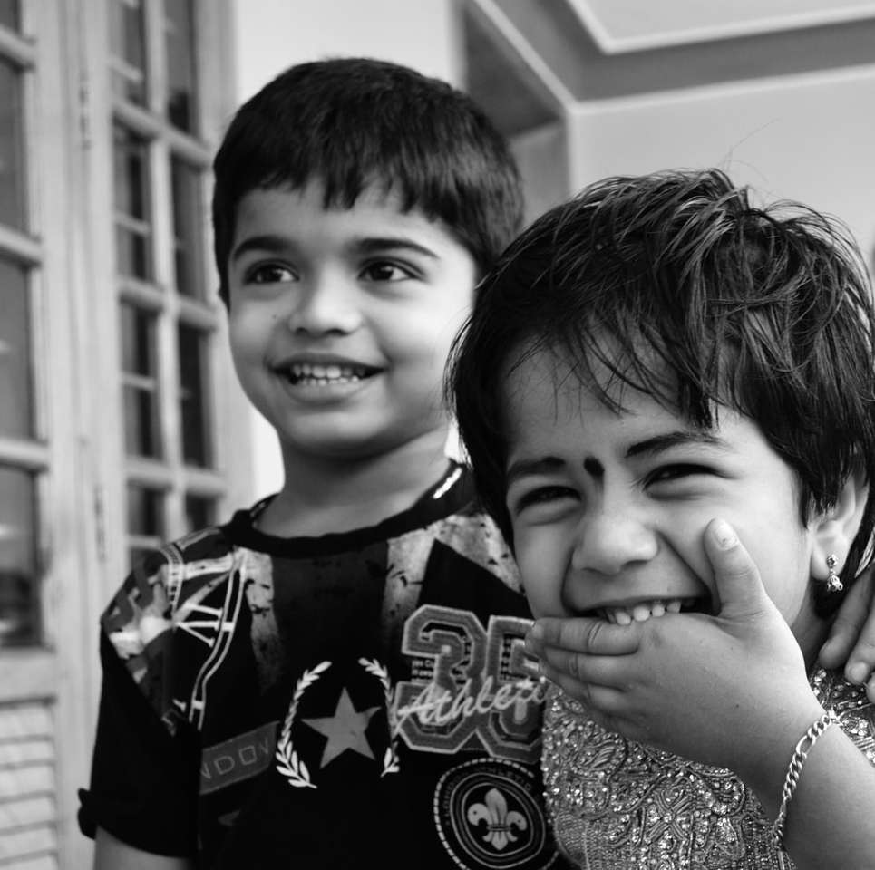 foto en escala de grises de 2 niños sonriendo rompecabezas en línea
