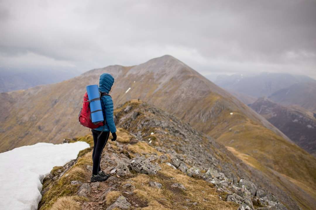 човек на върха на планината, носещ червена раница онлайн пъзел