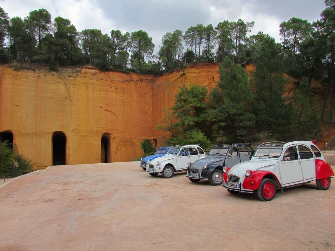 auto bianche e rosse parcheggiate accanto al muro di cemento marrone puzzle online