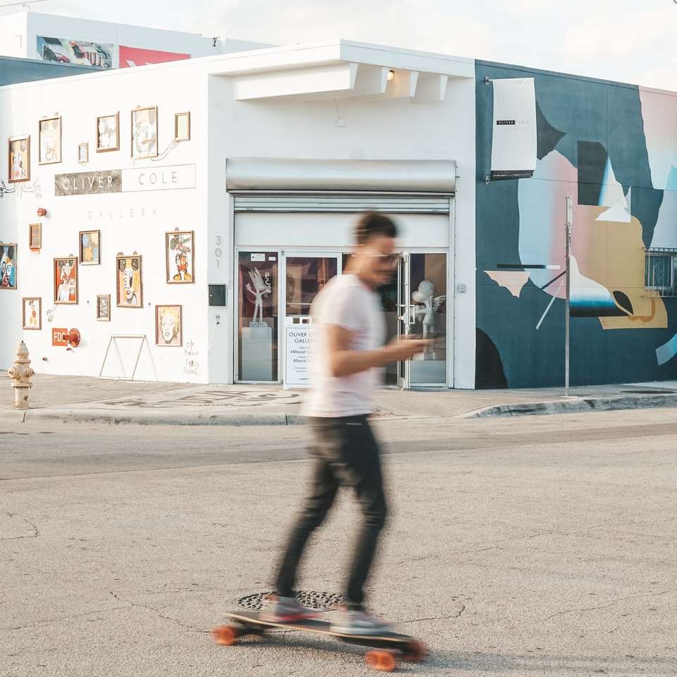man using longboard near white and teal structure online puzzle