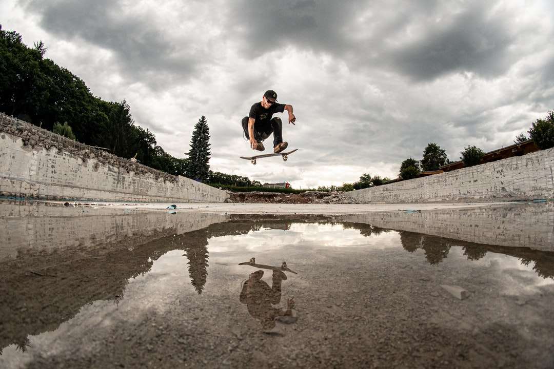 мужчина делает трюк на скейтборде над водой пазл онлайн