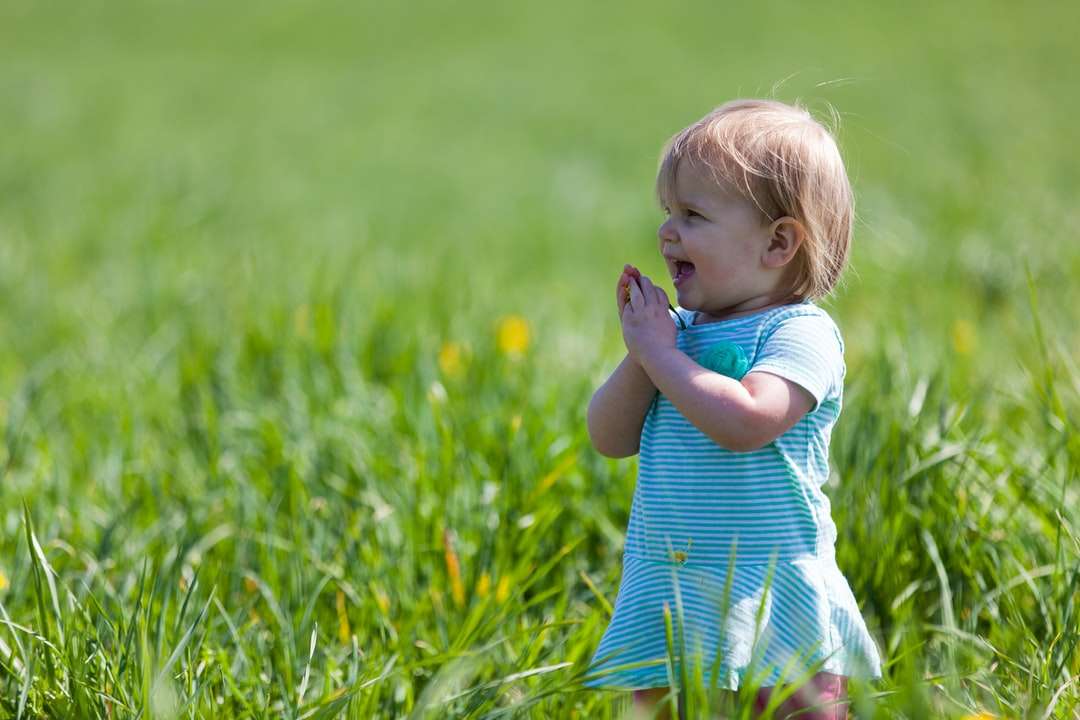 Niño con vestido verde azulado en campo de hierba verde durante el día rompecabezas en línea