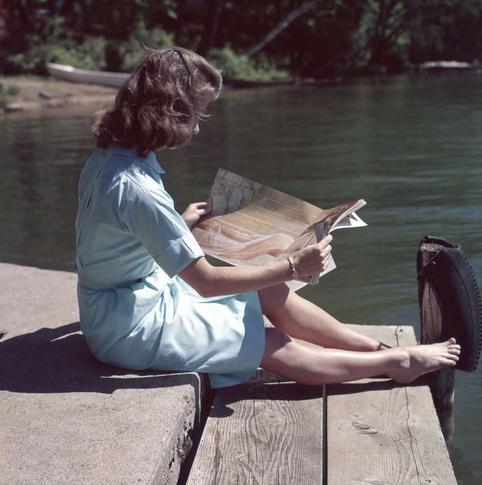 женщина в синем платье читает журнал рядом с телом онлайн-пазл