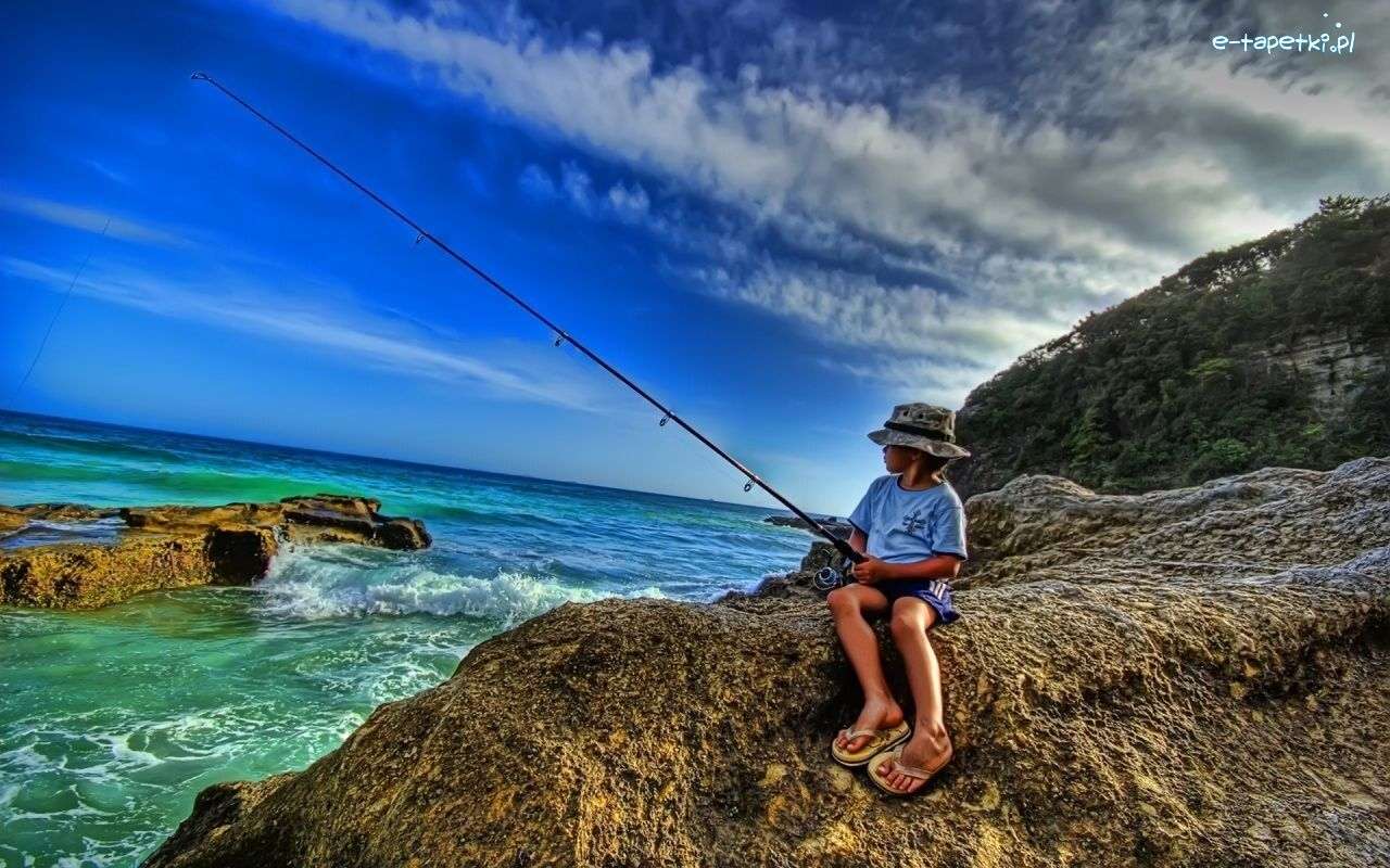 en pojke som sitter i en sluttning med en fiskespö Pussel online