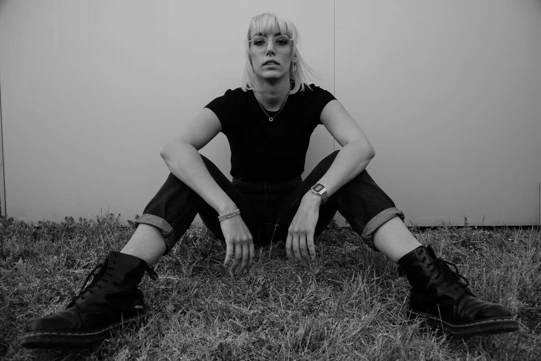 donna in camicia nera che si siede sull'erba puzzle online