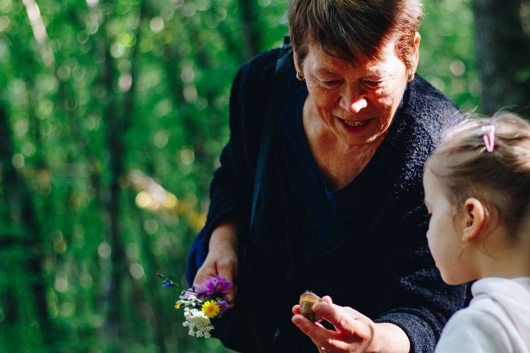 жена в черна риза с дълъг ръкав, държаща лилаво цвете онлайн пъзел