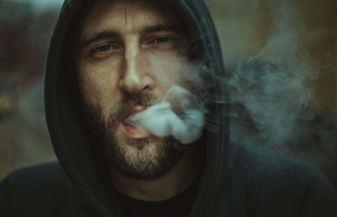 Homme portant un sweat à capuche noir soufflant de la fumée blanche puzzle en ligne