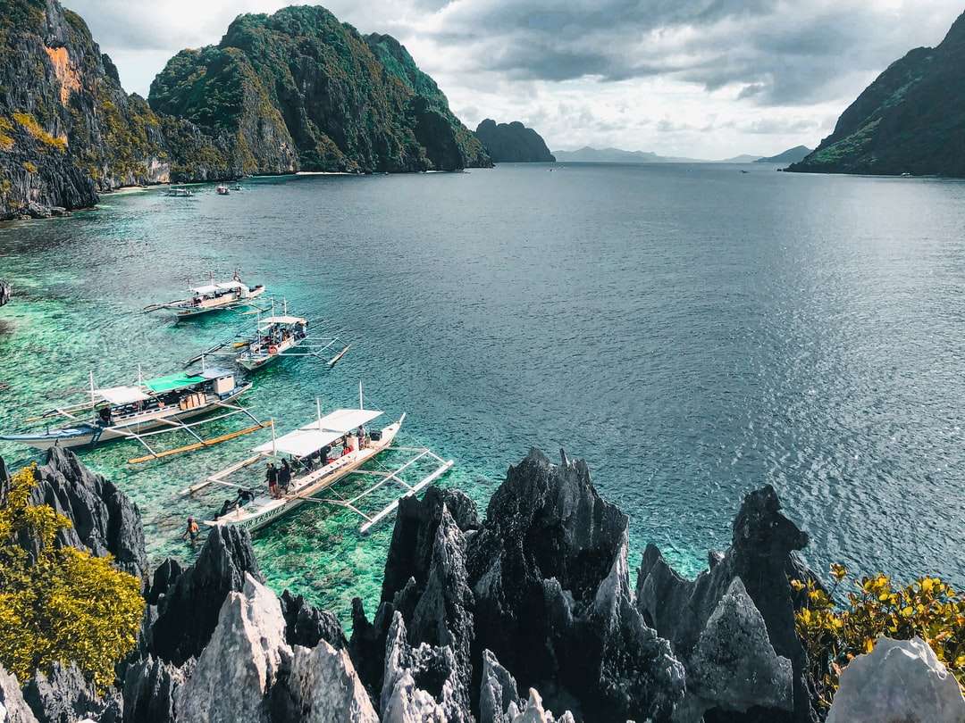 бяла и синя лодка на море в близост до зелена планина онлайн пъзел