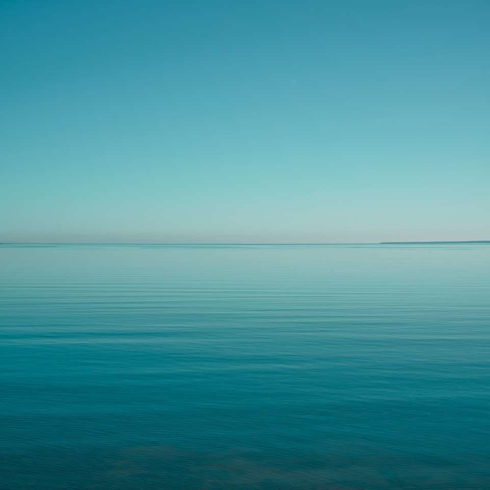água azul do oceano sob o céu azul durante o dia quebra-cabeças online