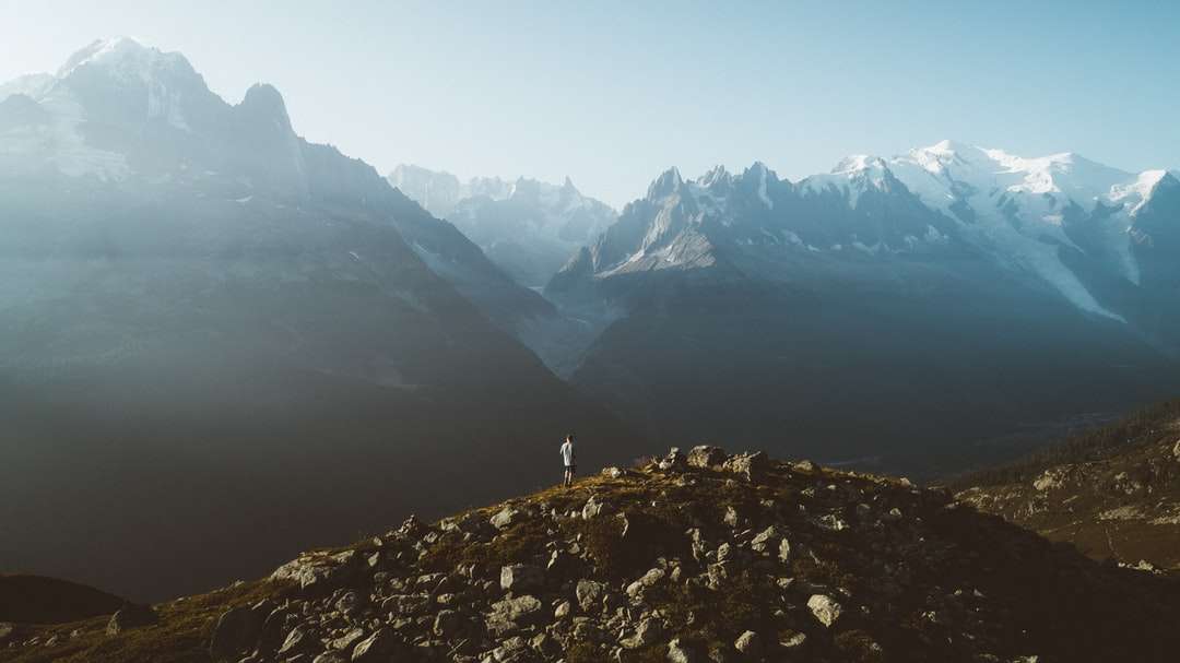 човек, стоящ на скалиста планина през деня онлайн пъзел