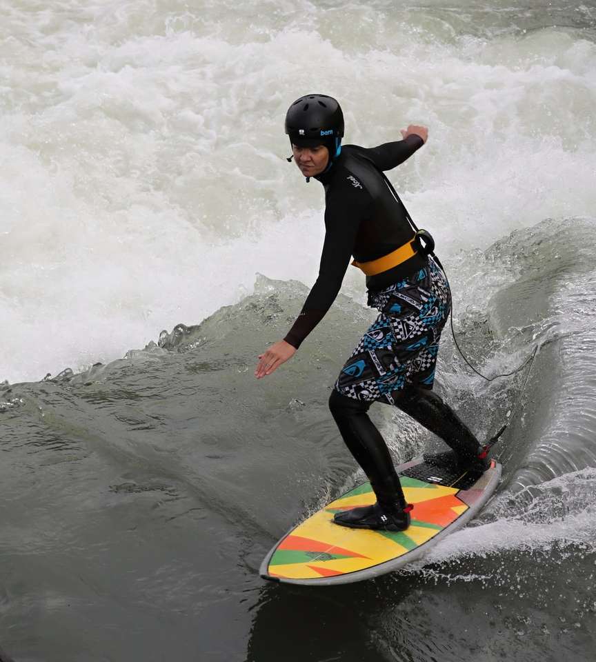 мъж в синьо-черен хидрокостюм, яздещ жълт сърф онлайн пъзел